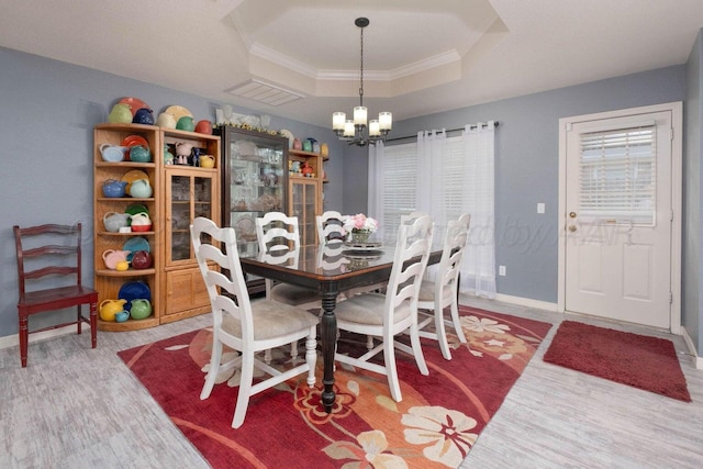 dining area featuring a tray ceiling, baseboards, a notable chandelier, and ornamental molding