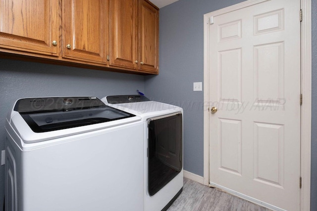 laundry area featuring cabinet space, washing machine and dryer, baseboards, and light wood finished floors