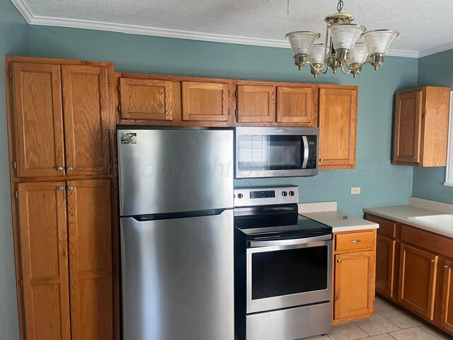 2409 S Tyler St, Amarillo, TX 79109 - kitchen featuring appliances with stainless steel finishes, light countertops, brown cabinetry, ornamental molding, and a textured ceiling