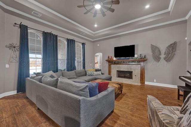 6905 Spring Cherry Ln, Amarillo, TX 79124 - living area with a ceiling fan, wood finished floors, a raised ceiling, a tiled fireplace, and crown molding