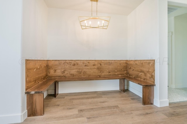 unfurnished dining area featuring light wood-style flooring and a notable chandelier