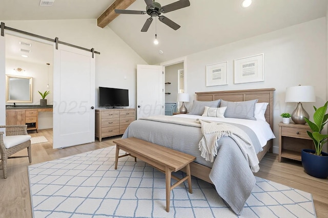 bedroom with vaulted ceiling with beams, a barn door, visible vents, and light wood-style flooring