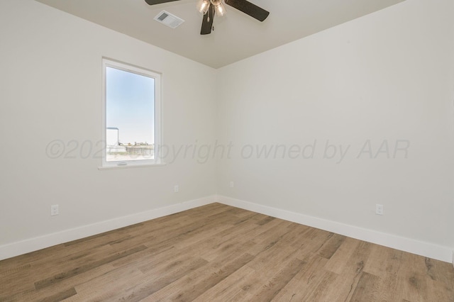 spare room with baseboards, a ceiling fan, visible vents, and light wood-style floors