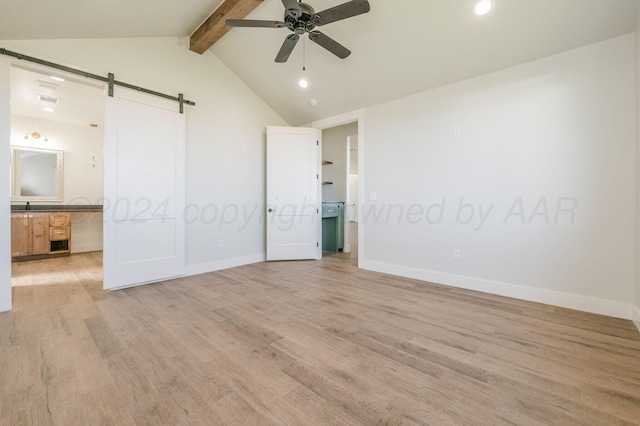 unfurnished bedroom featuring baseboards, vaulted ceiling with beams, light wood finished floors, and a barn door