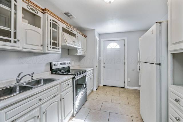 kitchen featuring visible vents, freestanding refrigerator, glass insert cabinets, stainless steel range with electric stovetop, and light countertops