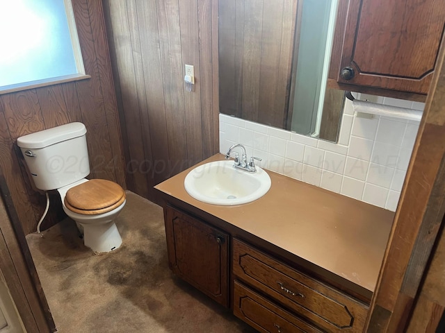 bathroom with tasteful backsplash, wood walls, vanity, and toilet