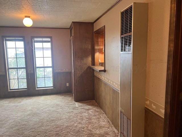 hall with light carpet, wood walls, and ornamental molding