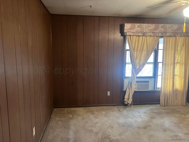 empty room with cooling unit, wood walls, carpet, and ceiling fan