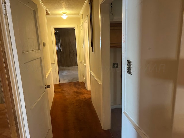 corridor with a textured ceiling and dark colored carpet