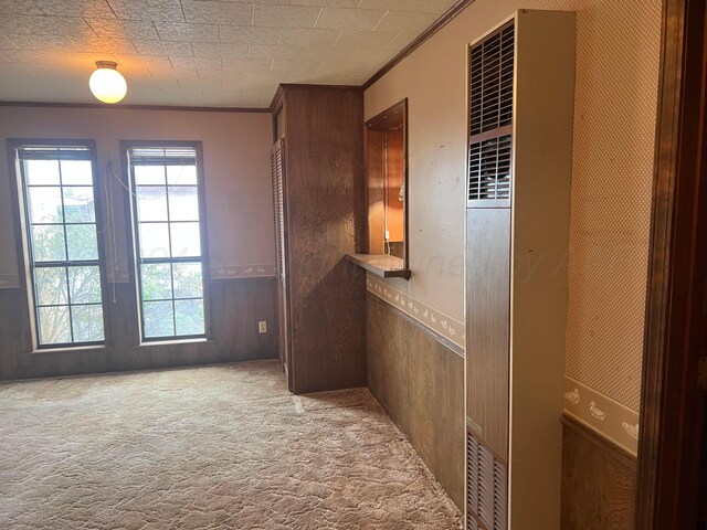 hall with light carpet, ornamental molding, and wood walls