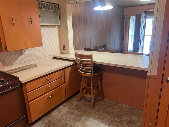 kitchen with kitchen peninsula, range, and a wall mounted AC