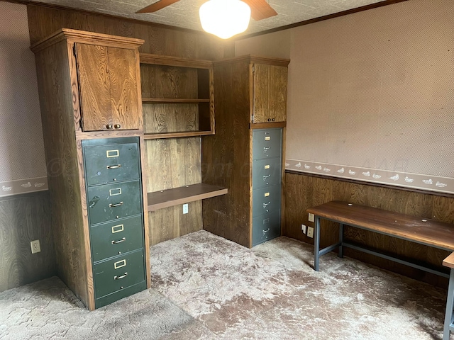 office featuring ceiling fan, wooden walls, and light carpet