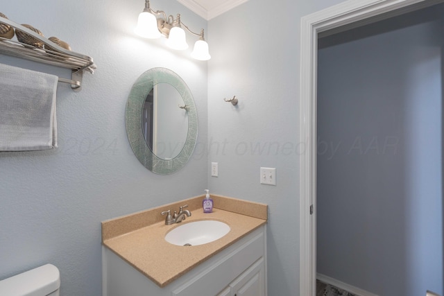 bathroom with toilet, vanity, and ornamental molding