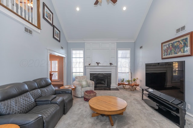 living room featuring crown molding, ceiling fan, a fireplace, and light colored carpet