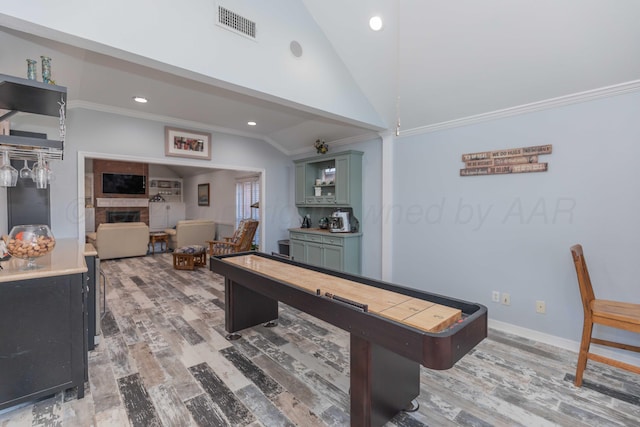 game room featuring hardwood / wood-style flooring, vaulted ceiling, and ornamental molding