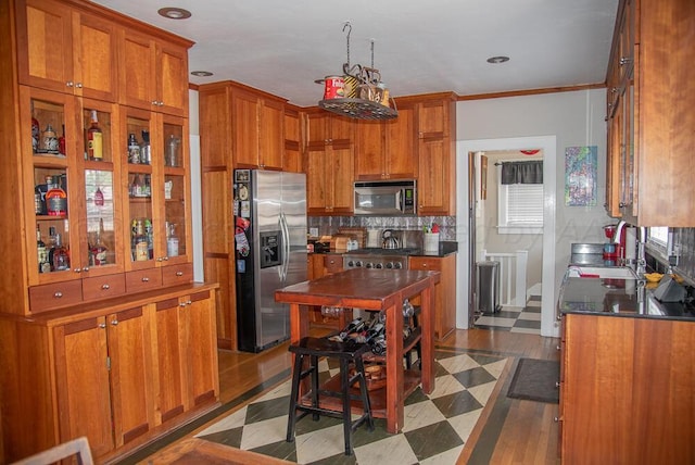 2122 S Hayden St, Amarillo, TX 79109 - kitchen featuring appliances with stainless steel finishes, brown cabinetry, dark countertops, tasteful backsplash, and dark flooring