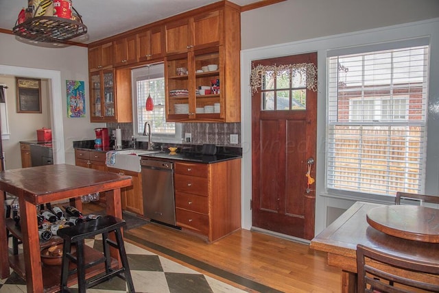 2122 S Hayden St, Amarillo, TX 79109 - kitchen featuring stainless steel dishwasher, brown cabinets, wood finished floors, glass insert cabinets, and dark countertops