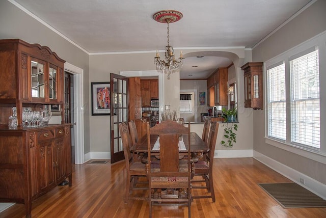 2122 S Hayden St, Amarillo, TX 79109 - dining room featuring light wood finished floors, arched walkways, a chandelier, and ornamental molding