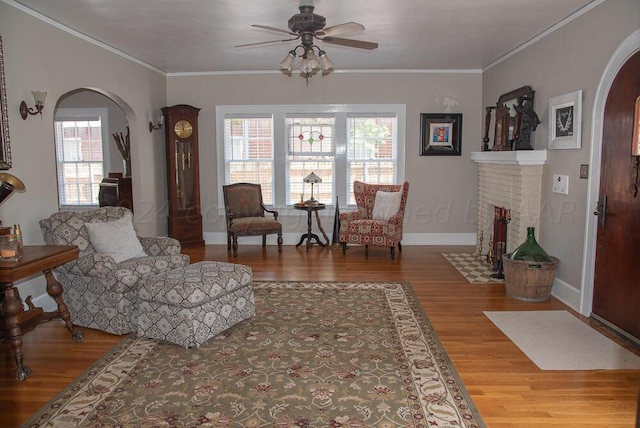 2122 S Hayden St, Amarillo, TX 79109 - living area featuring arched walkways, ceiling fan, wood finished floors, a brick fireplace, and crown molding