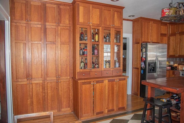 2122 S Hayden St, Amarillo, TX 79109 - kitchen with stainless steel fridge, brown cabinetry, light wood-style flooring, and glass insert cabinets