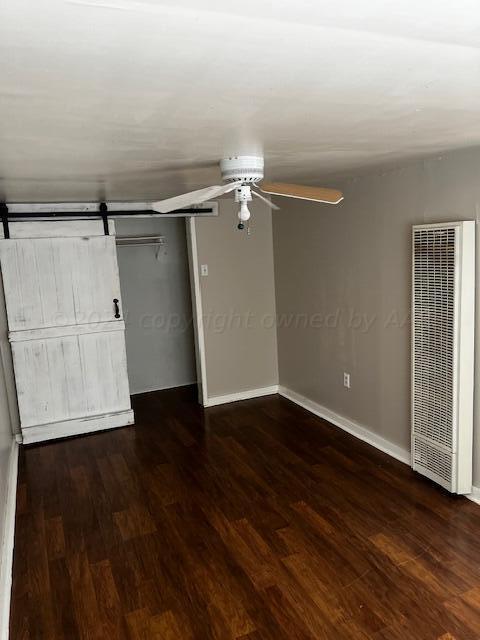 2122 S Hayden St, Amarillo, TX 79109 - unfurnished bedroom with a heating unit, dark wood finished floors, ceiling fan, a closet, and a barn door