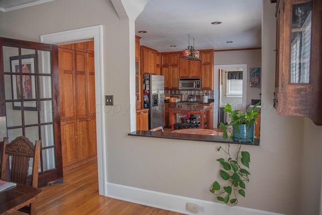 2122 S Hayden St, Amarillo, TX 79109 - kitchen featuring appliances with stainless steel finishes, wood finished floors, dark countertops, ornamental molding, and brown cabinets