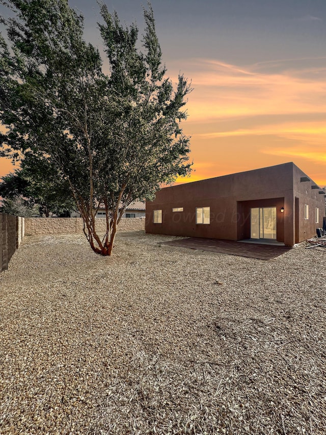 back house at dusk featuring a patio area