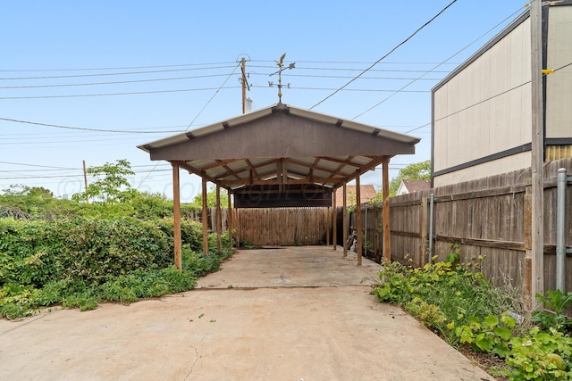 view of car parking with a carport, fence, and concrete driveway