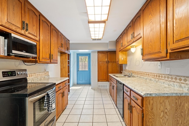 kitchen featuring stainless steel electric range, brown cabinetry, light countertops, a sink, and light tile patterned floors