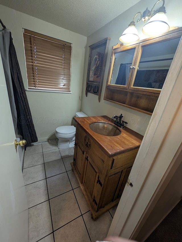 full bath featuring tile patterned floors, toilet, vanity, and a textured ceiling