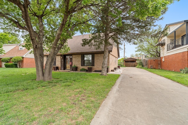 mid-century modern home featuring a front lawn, concrete driveway, brick siding, and roof with shingles