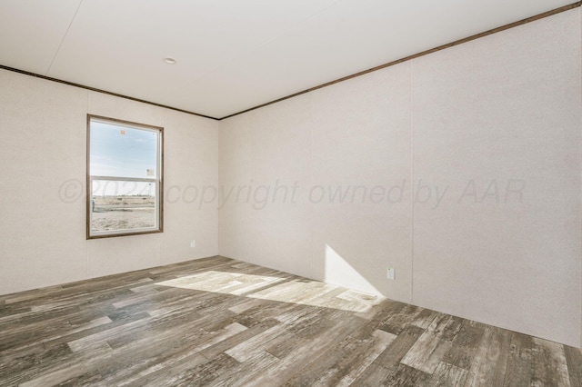 empty room with hardwood / wood-style floors and crown molding