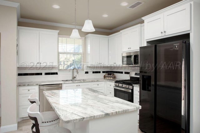 kitchen featuring a kitchen island, sink, white cabinets, hanging light fixtures, and stainless steel appliances