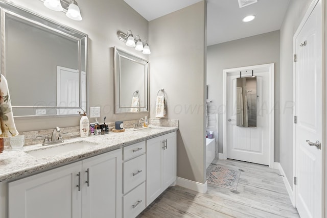 6702 Tatum Cir, Amarillo, TX 79119 - full bathroom featuring double vanity, wood finished floors, a garden tub, and baseboards
