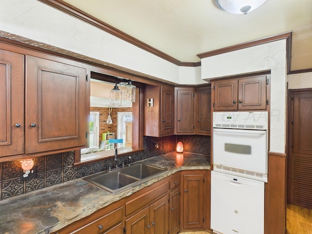 317 Morton Ave, Dumas, TX 79029 - kitchen featuring white appliances, decorative backsplash, ornamental molding, pendant lighting, and light wood-style flooring