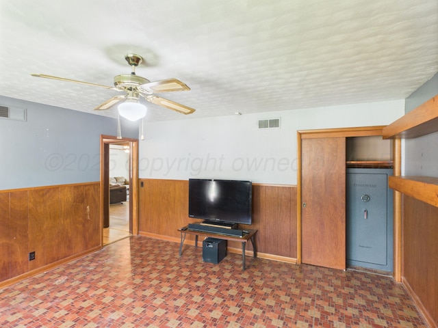317 Morton Ave, Dumas, TX 79029 - living area featuring wood walls, wainscoting, ceiling fan, and tile patterned floors