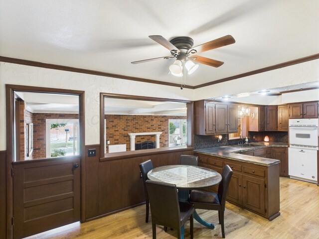 317 Morton Ave, Dumas, TX 79029 - kitchen featuring white appliances, dark countertops, light wood-style floors, wainscoting, and ceiling fan