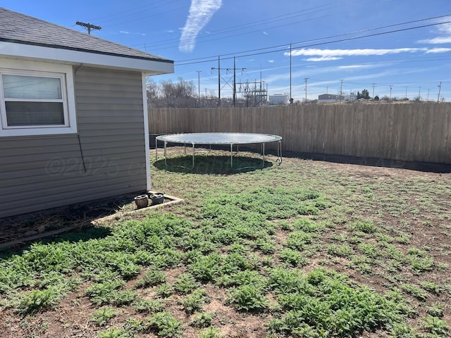 view of yard featuring a trampoline and fence