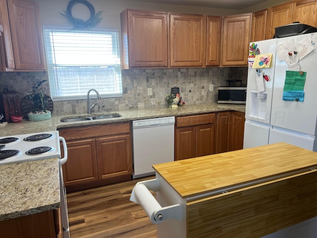 kitchen with a sink, decorative backsplash, white appliances, and wood finished floors