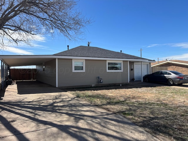 view of front of property with an attached carport, fence, a shingled roof, concrete driveway, and a garage