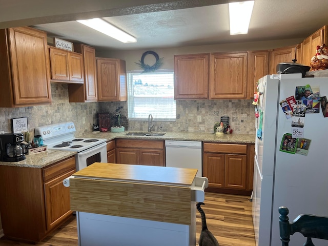 kitchen with white appliances, a center island, light wood-style floors, and a sink