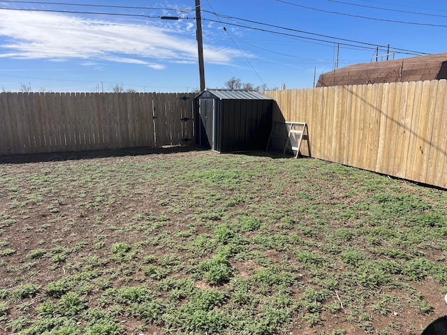 view of yard featuring a storage unit, a fenced backyard, and an outdoor structure