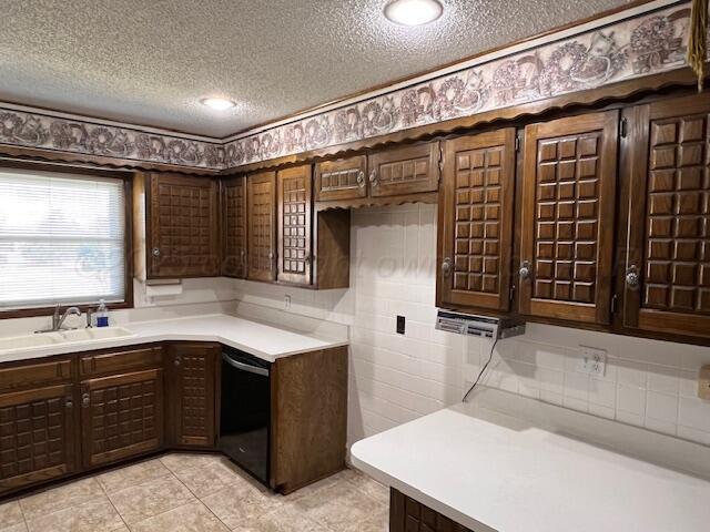 3102 S Main St, Perryton, TX 79070 - kitchen with black dishwasher, a textured ceiling, light countertops, dark brown cabinetry, and light tile patterned flooring