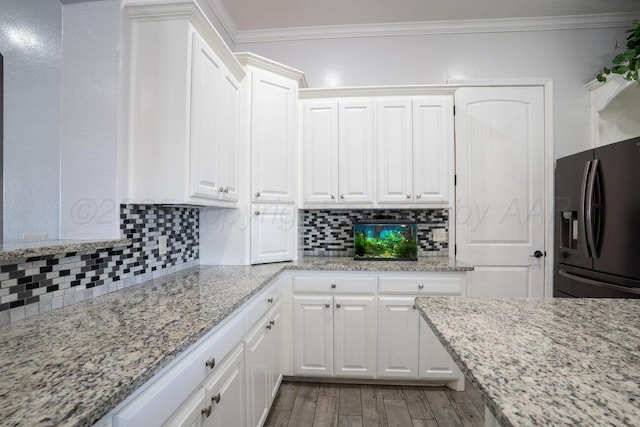 8121 Alexandria Ave, Amarillo, TX 79118 - kitchen with black fridge, white cabinetry, crown molding, and decorative backsplash
