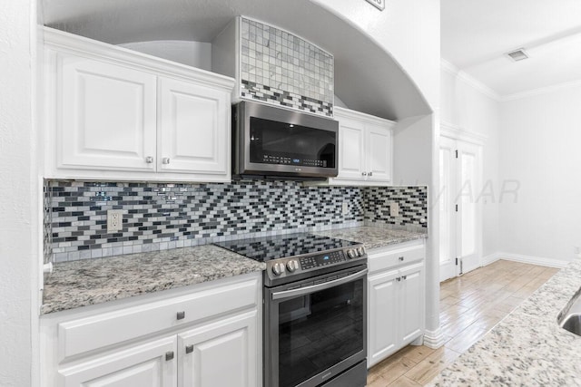 8121 Alexandria Ave, Amarillo, TX 79118 - kitchen with stainless steel appliances, white cabinetry, light wood-style floors, ornamental molding, and tasteful backsplash