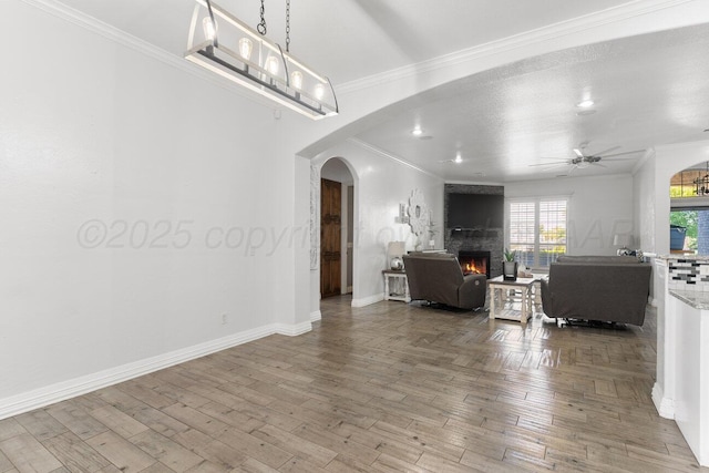 8121 Alexandria Ave, Amarillo, TX 79118 - living room featuring arched walkways, a fireplace, a ceiling fan, crown molding, and wood finished floors