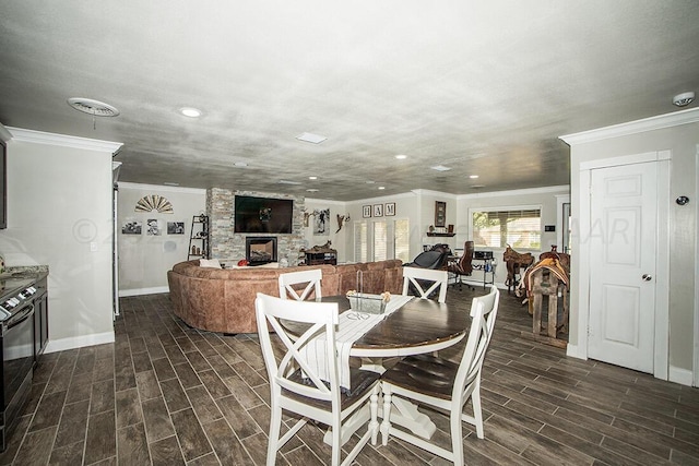 dining area featuring crown molding, wood tiled floor, visible vents, and a fireplace