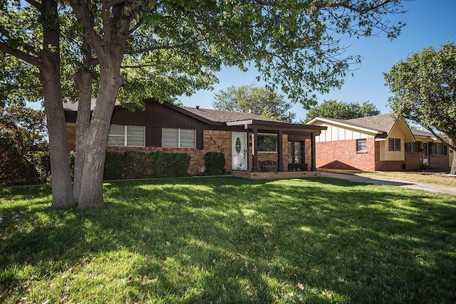 view of front facade with brick siding, board and batten siding, and a front yard