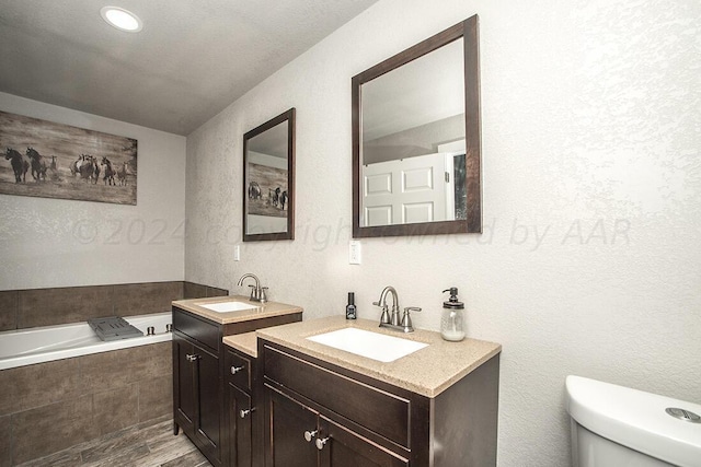 bathroom featuring a bath, toilet, a sink, and wood finished floors