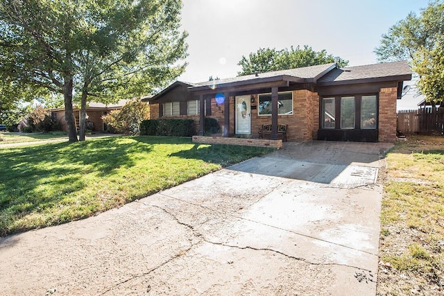 ranch-style home with a front lawn, fence, and brick siding